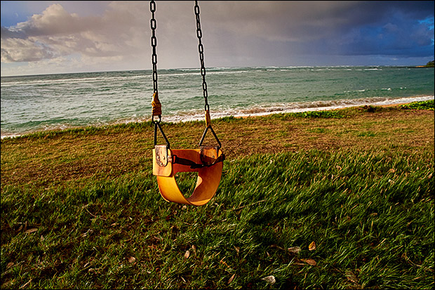 Rusty swing and seashore. Kauai, HI